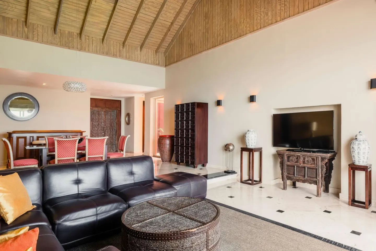 Suite living room with black sofa and vaulted ceiling at JOIA Rose Hall by Iberostar.