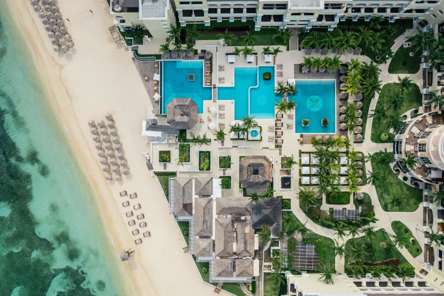 Top-down aerial view of pools, beach, and gardens at JOIA Rose Hall by Iberostar.