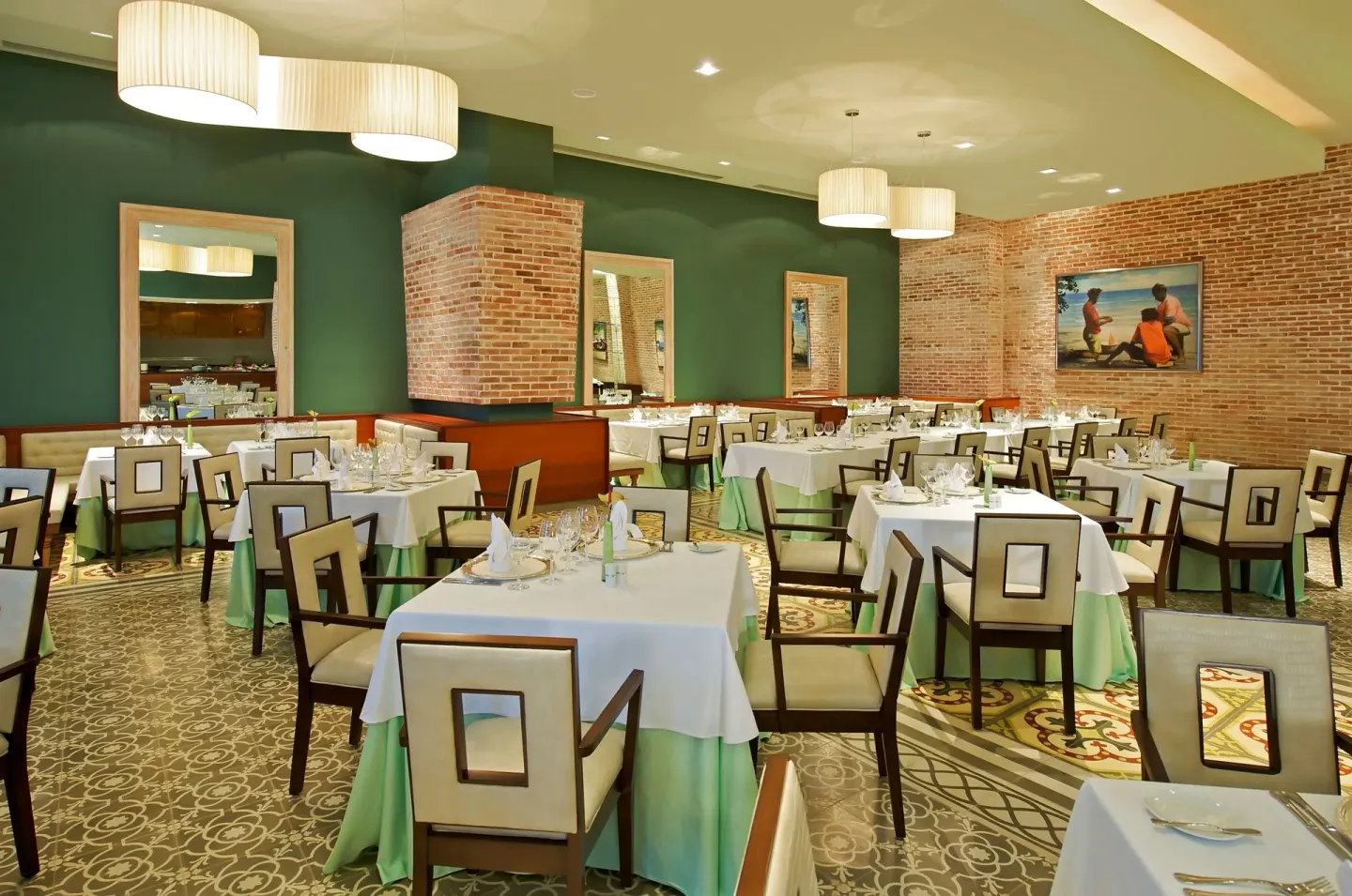 Formal dining room with brick walls and set tables at JOIA Rose Hall by Iberostar.