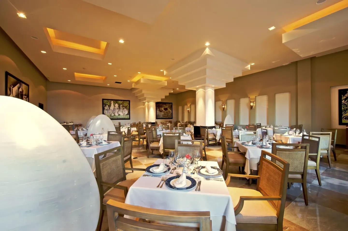 Elegant restaurant dining room with white table settings at JOIA Rose Hall by Iberostar.
