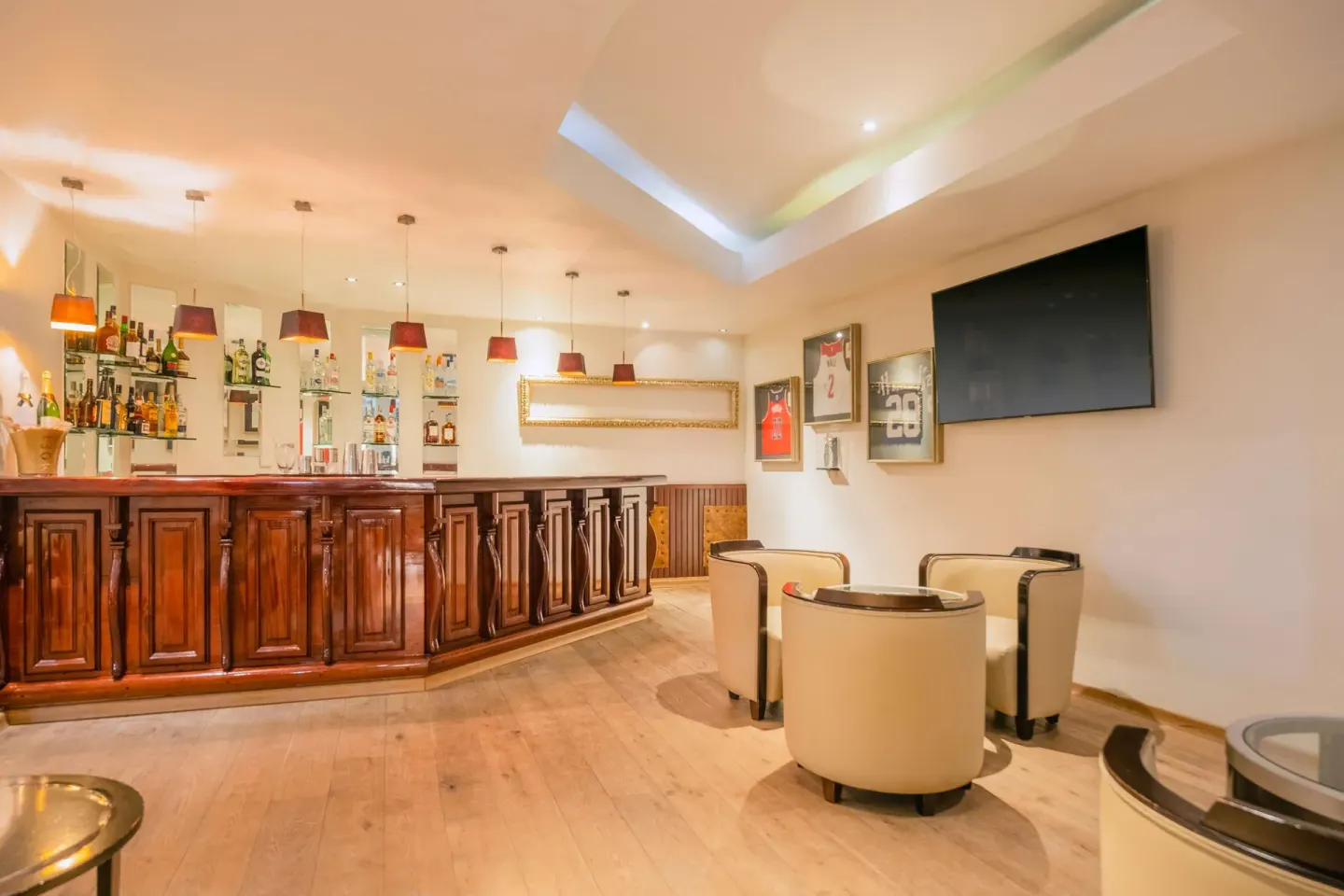 Sports bar with wood counter and wall-mounted television at JOIA Rose Hall by Iberostar.