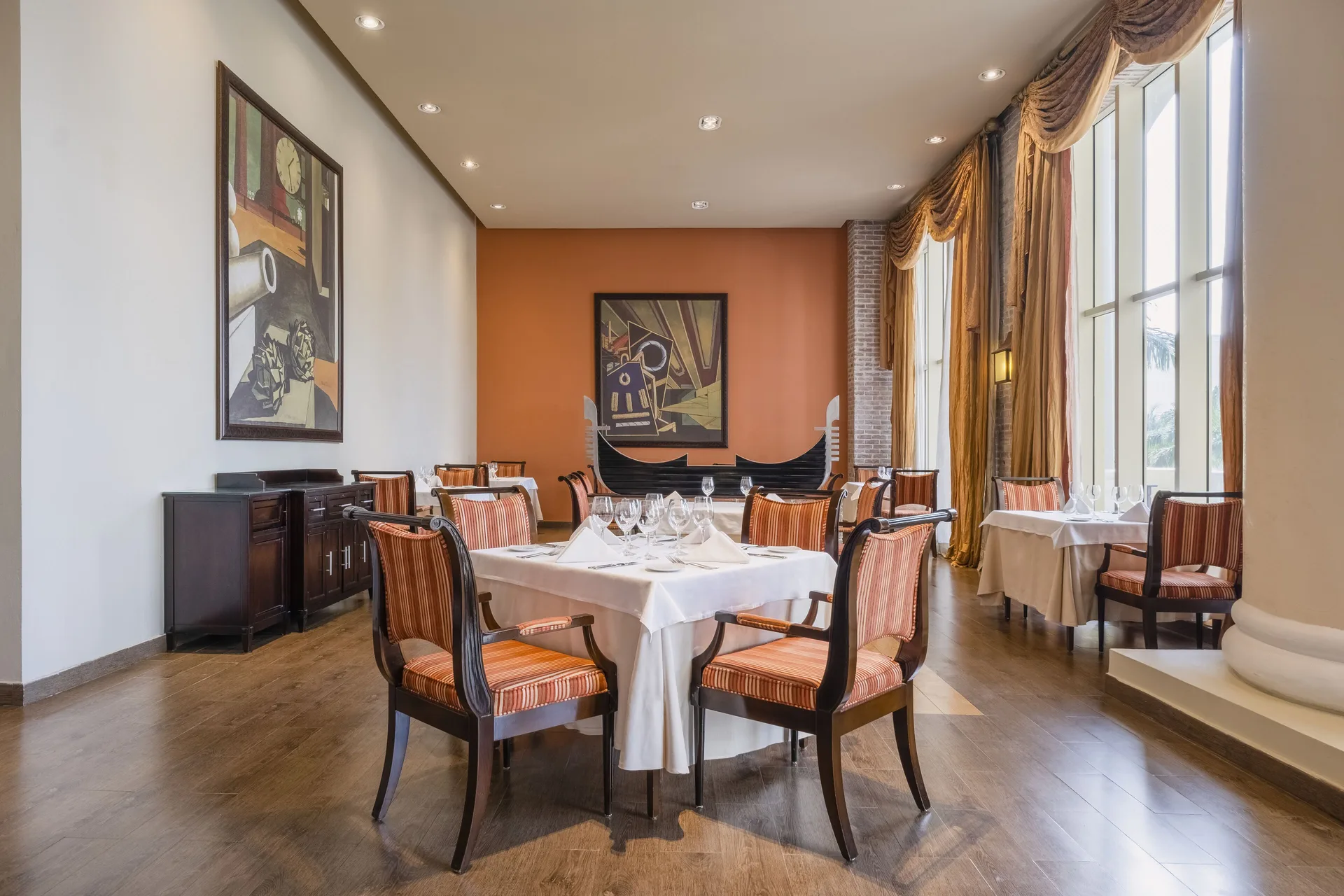 Italian-style dining room with tall windows and striped chairs at JOIA Rose Hall by Iberostar.