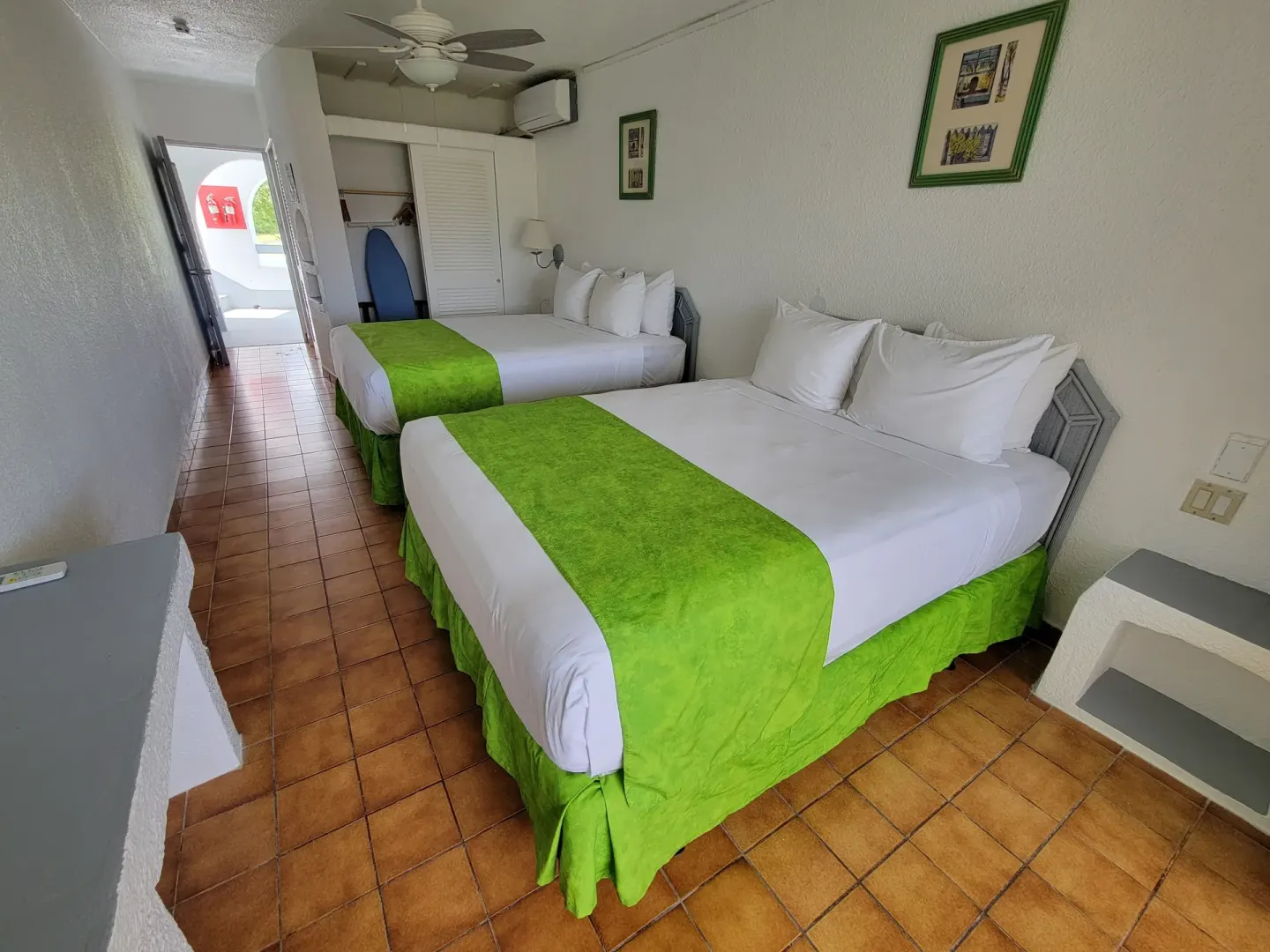 Two-bed guest room with closet and terracotta tile floor at Jolly Beach Antigua.