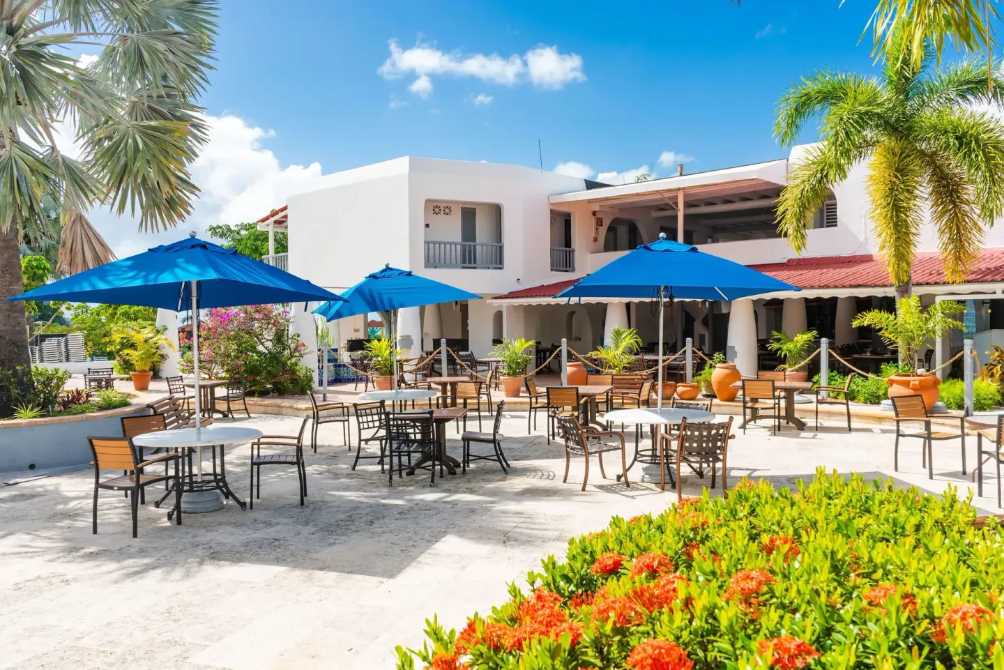 Outdoor courtyard seating with blue umbrellas and tropical landscaping at Jolly Beach Antigua.