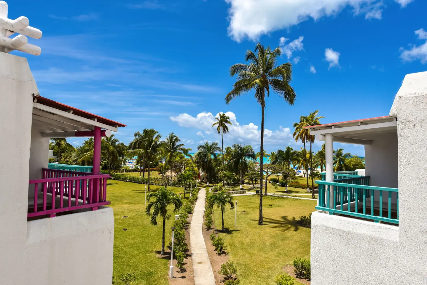 Palm-lined resort walkway between balcony buildings facing the sea at Jolly Beach Antigua.