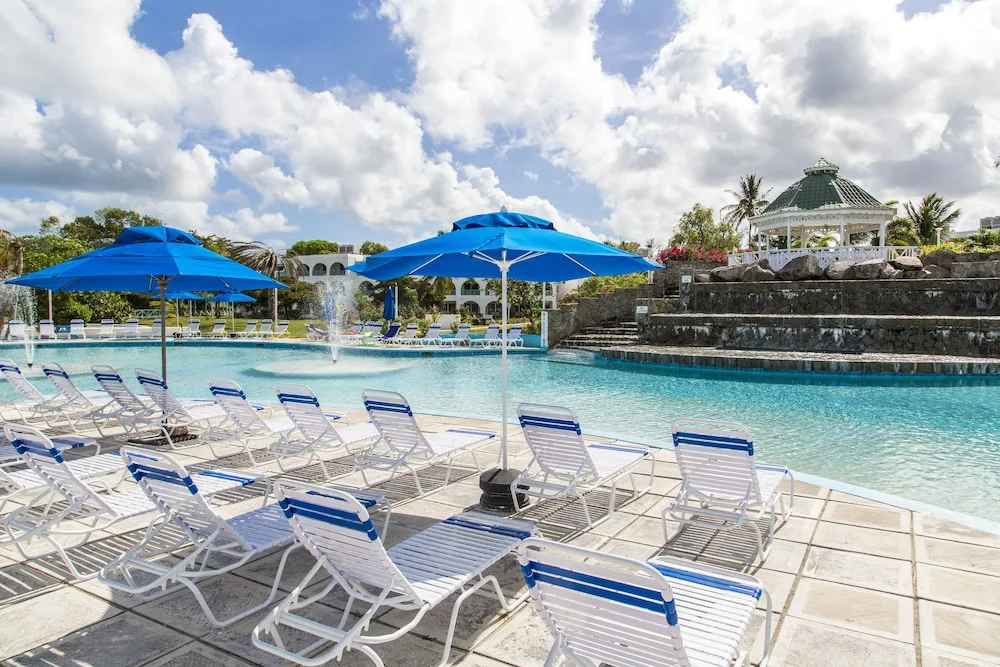 Pool loungers and blue umbrellas beside the swimming pool at Jolly Beach Antigua.