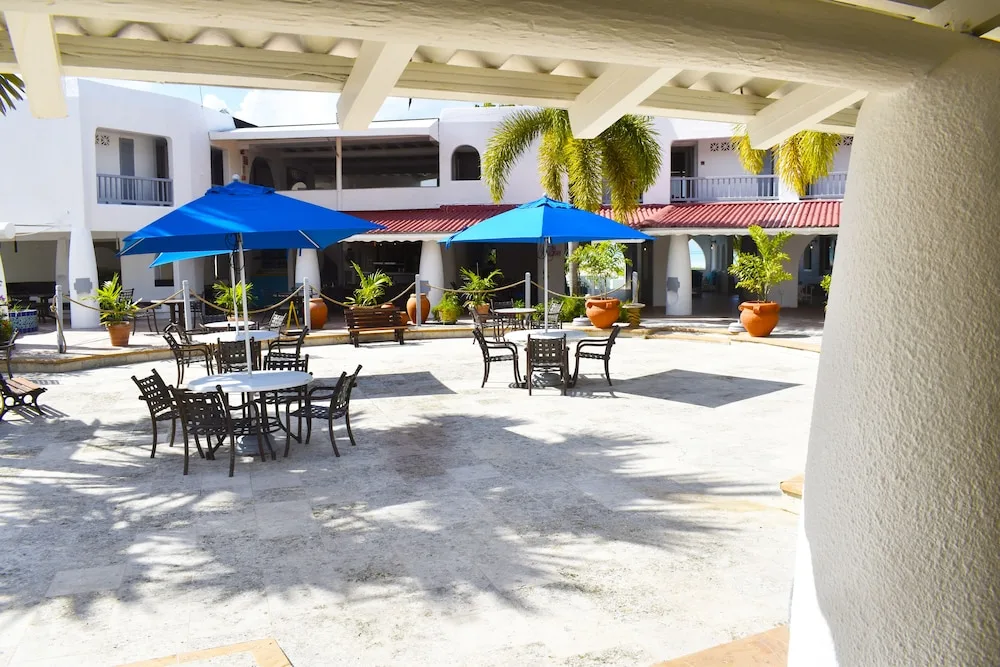 Resort courtyard with patio tables and blue umbrellas at Jolly Beach Antigua.