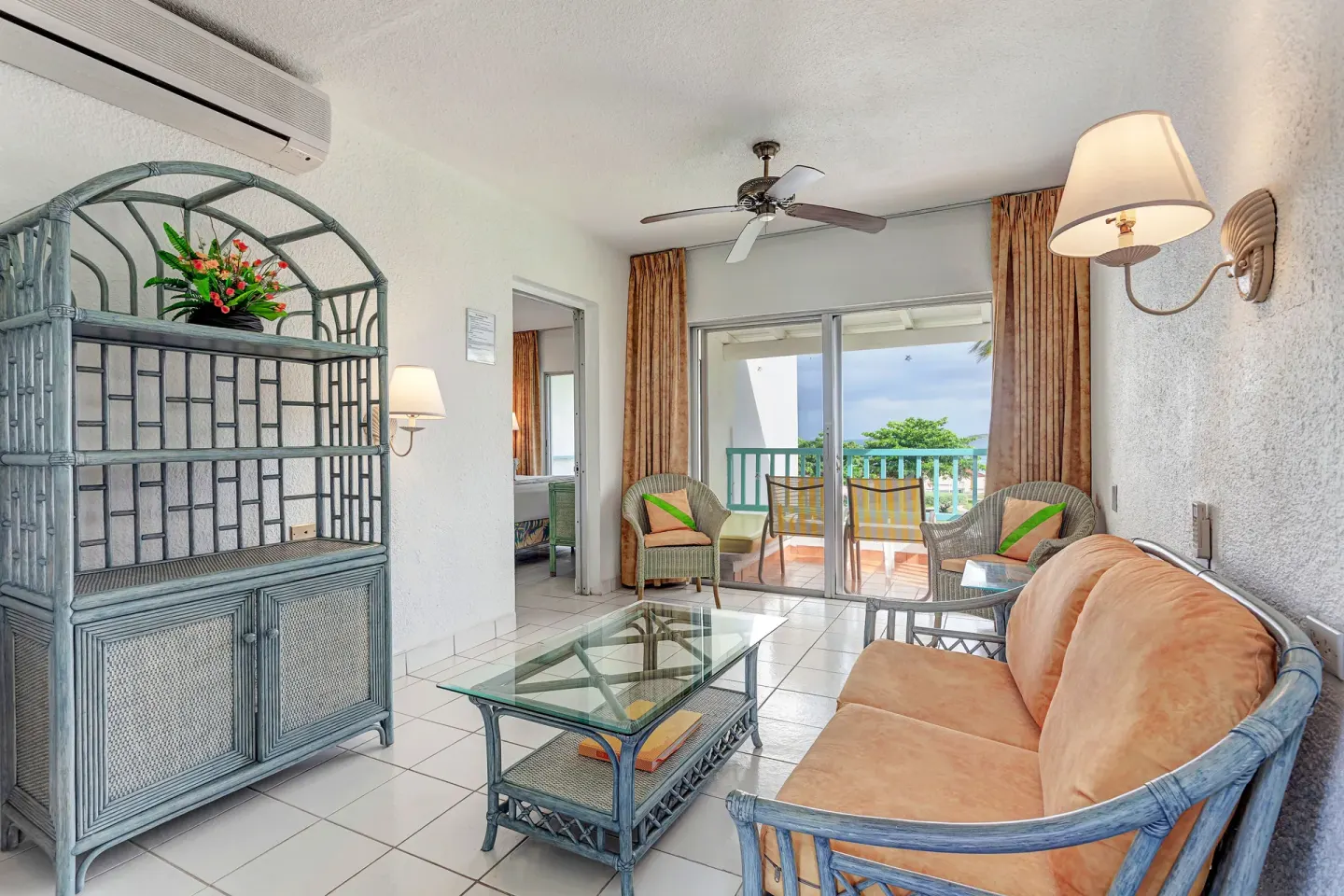 Suite living room with sofa, glass table and balcony view at Jolly Beach Antigua.