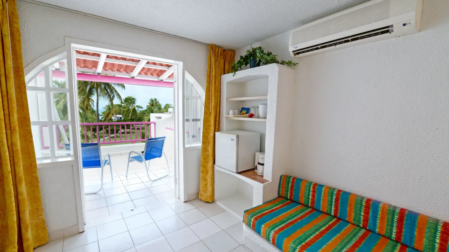 Suite sitting area with striped sofa and terrace doors at Jolly Beach Antigua.