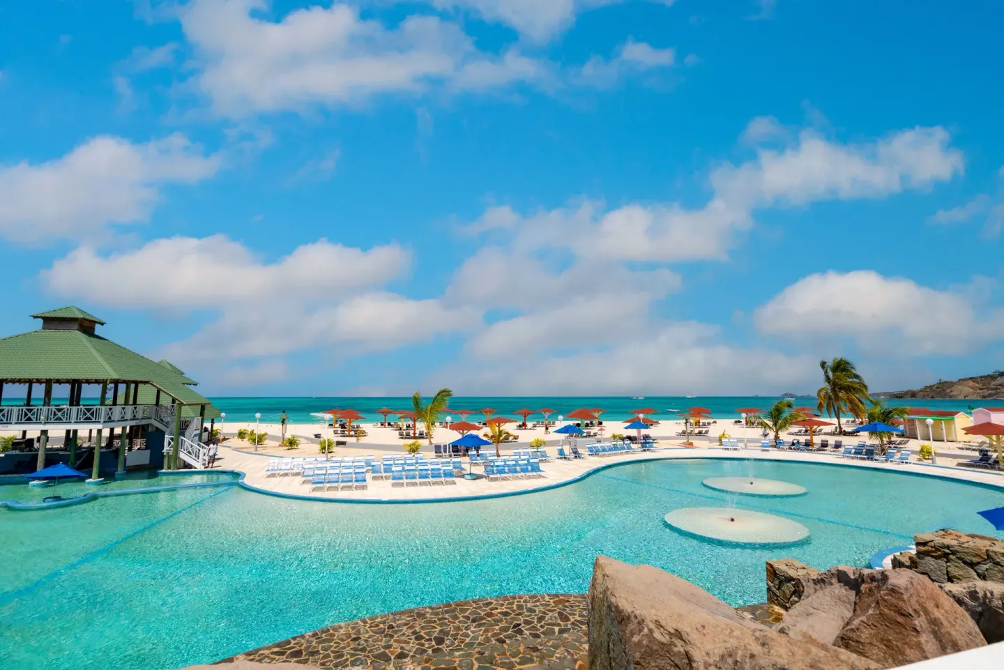 Wide pool and beach scene with blue sky at Jolly Beach Antigua.