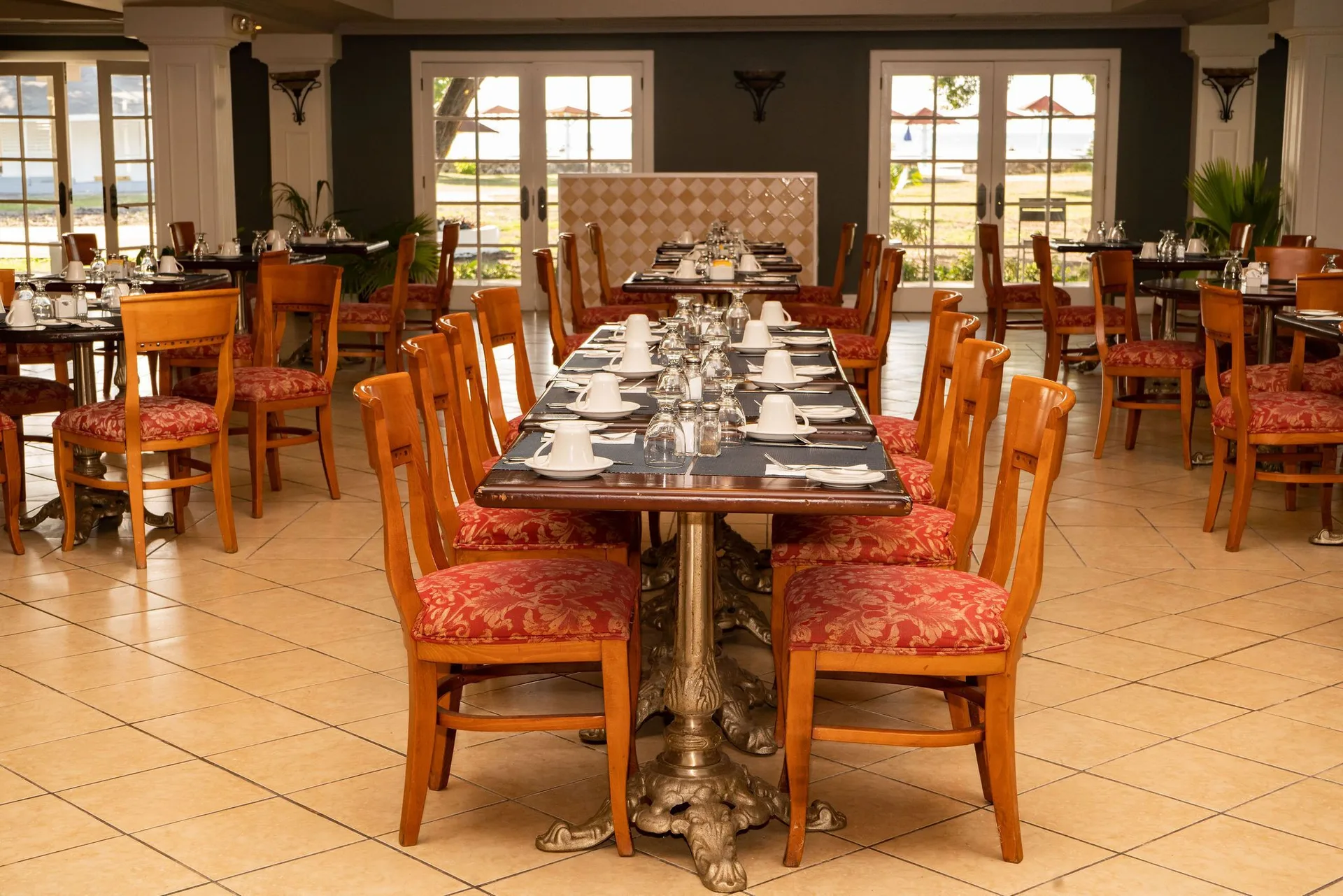 Indoor dining room with red cushioned chairs and set tables at Jolly Beach Antigua.