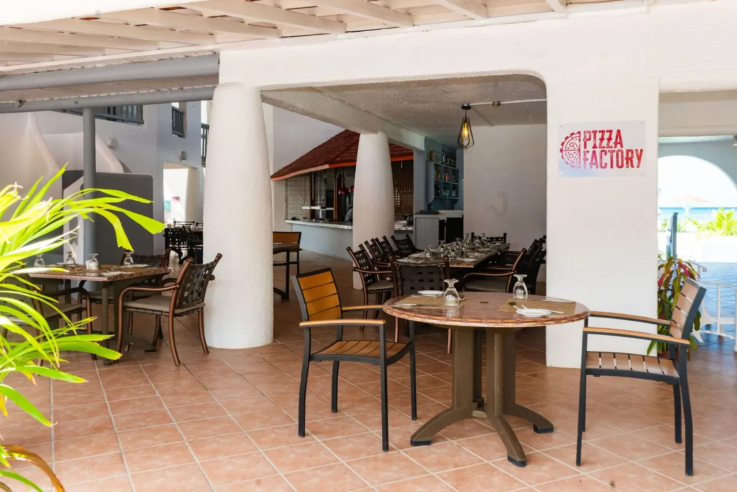 Pizza Factory seating area with sign and set tables at Jolly Beach Antigua.