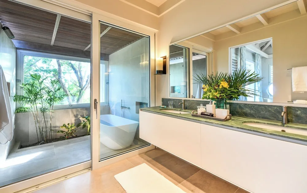 Bathroom vanity and glass-enclosed outdoor tub area at Jumby Bay Island.