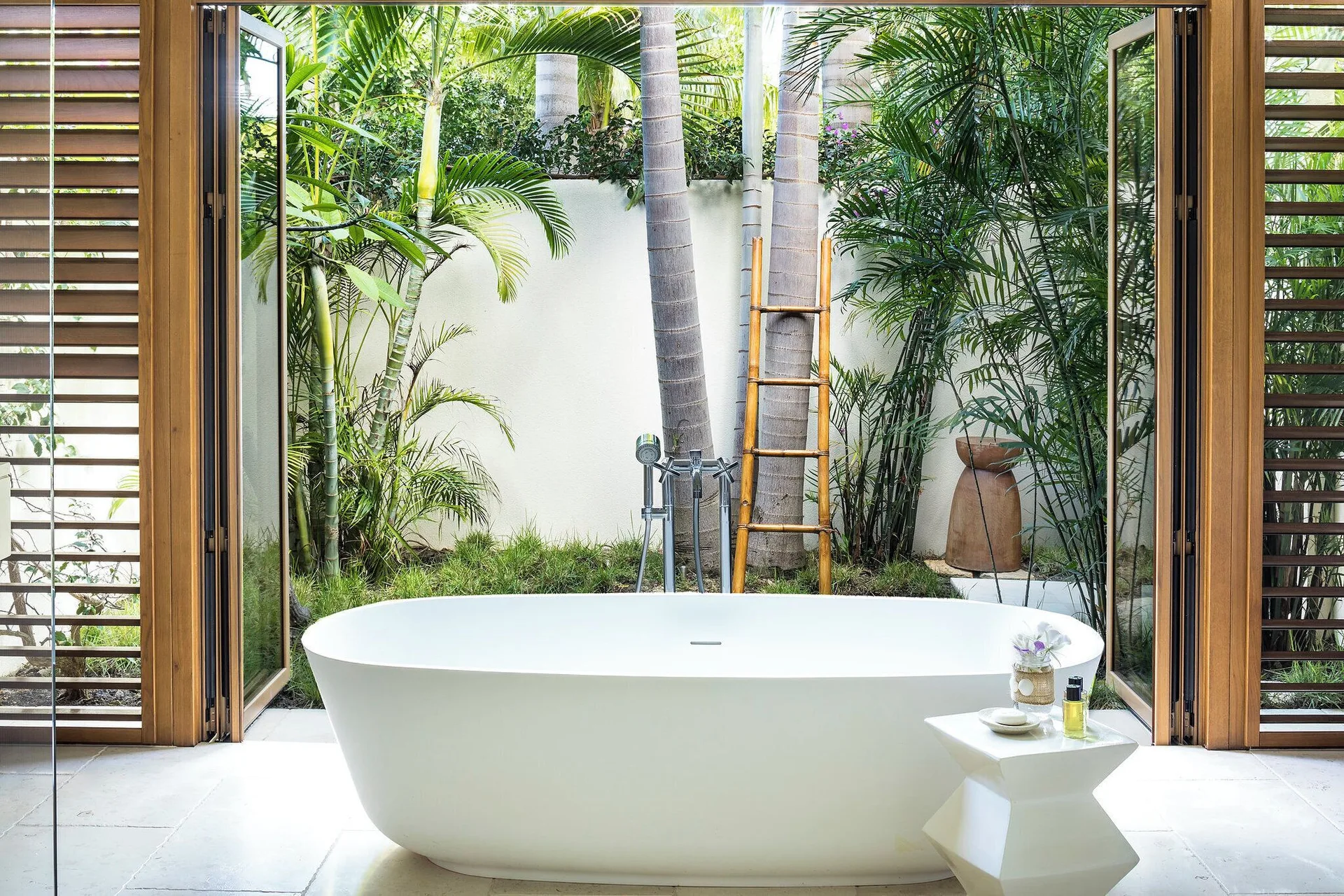 Freestanding bath opens to a private palm garden at Jumby Bay Island.