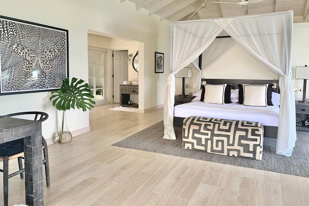Guest room with a canopy king bed and black-and-white accents at Jumby Bay Island.