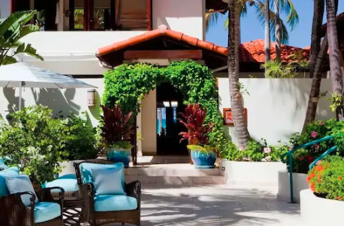 Tropical courtyard entrance with blue-cushioned seating at Jumby Bay Island.