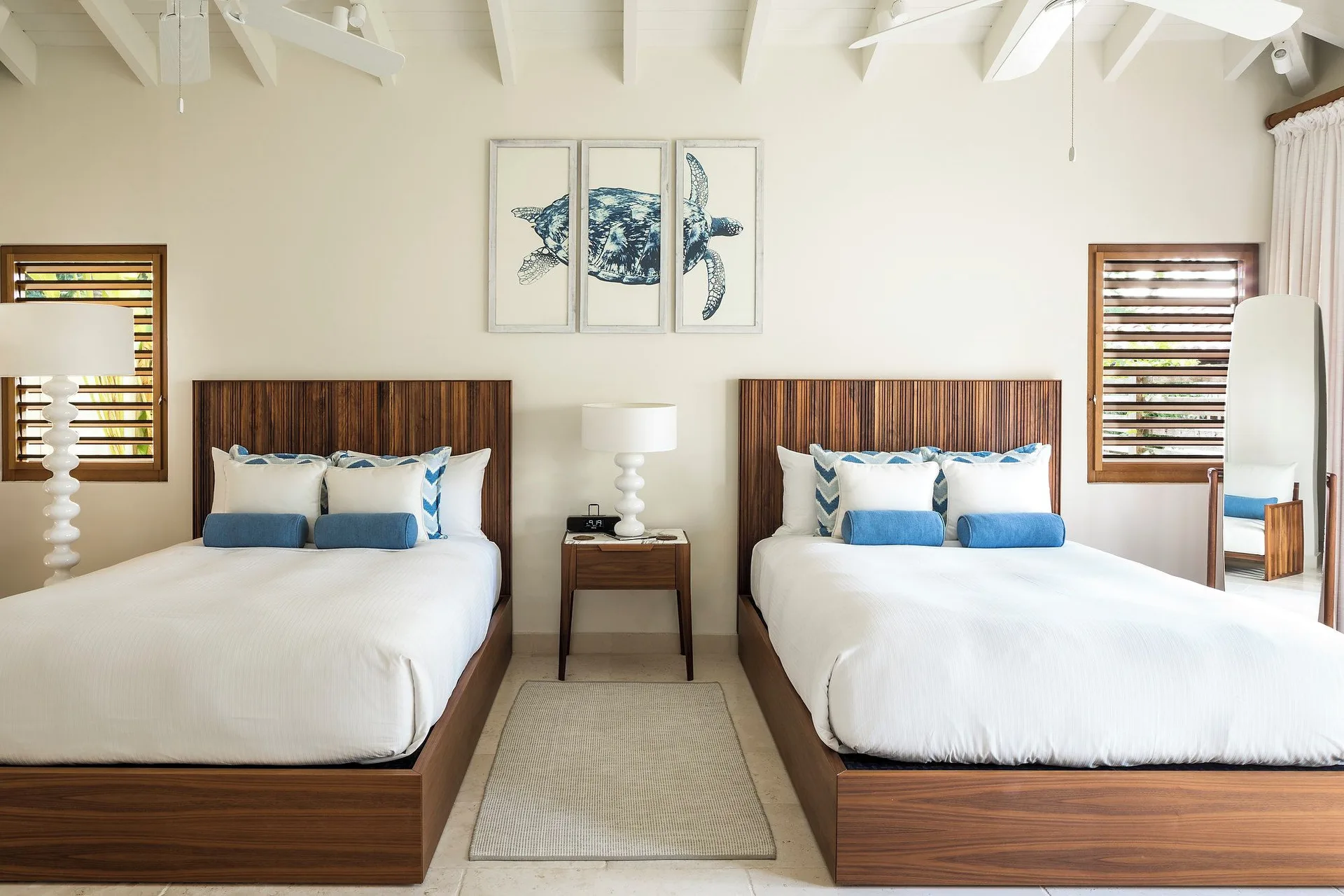 Allamanda bedroom with two beds, wood headboards and turtle artwork at Jumby Bay Island.