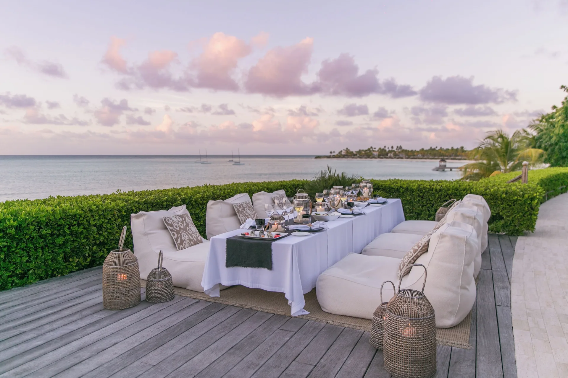 Calabash outdoor dining terrace at Jumby Bay Island set beside the water at sunset.