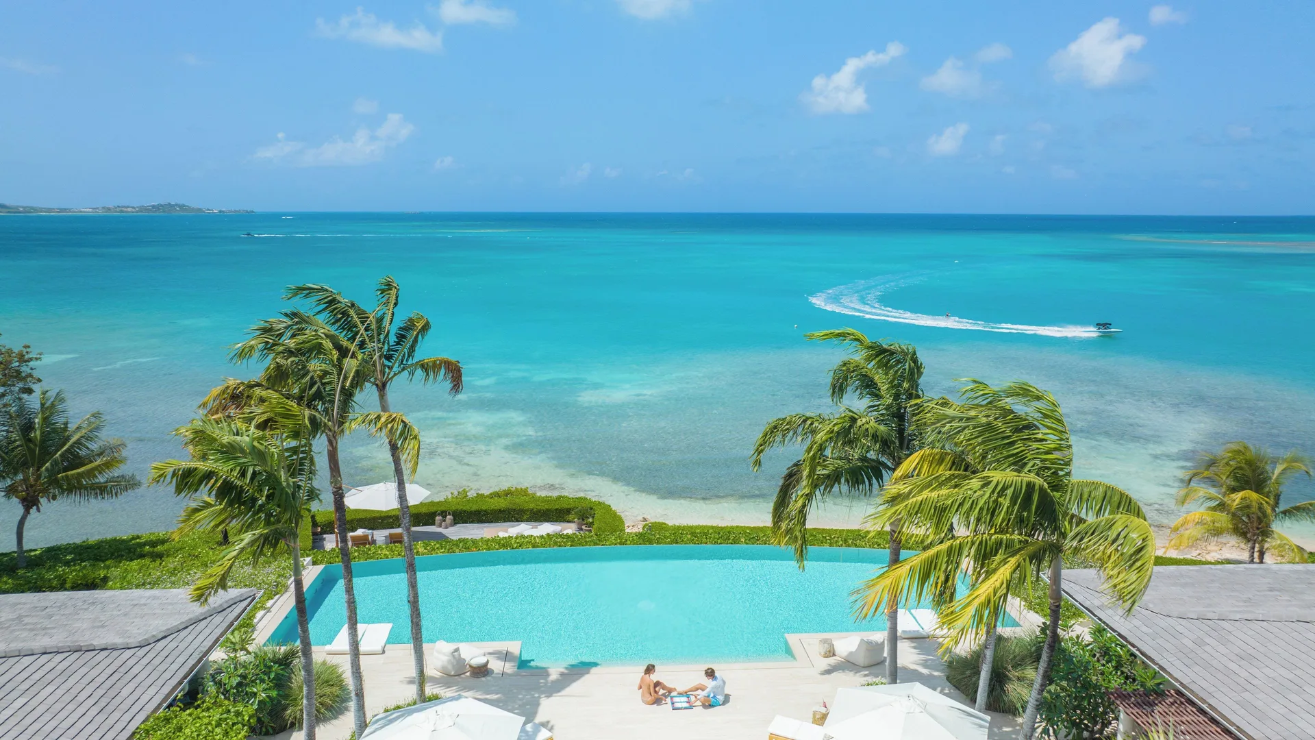 Calabash pool at Jumby Bay Island overlooking turquoise water and palm trees.