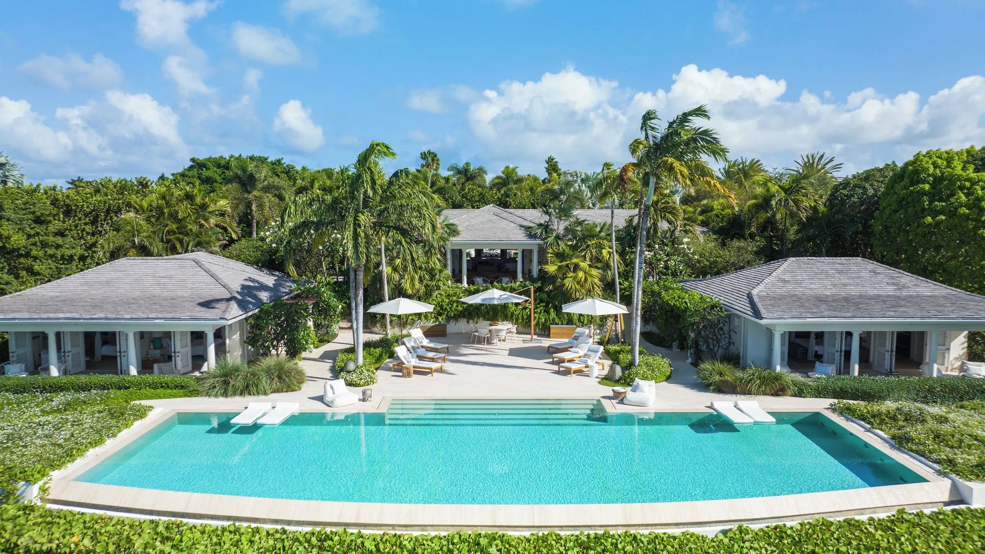 Calabash villa pool at Jumby Bay Island with lounge chairs, umbrellas, and tropical landscaping.