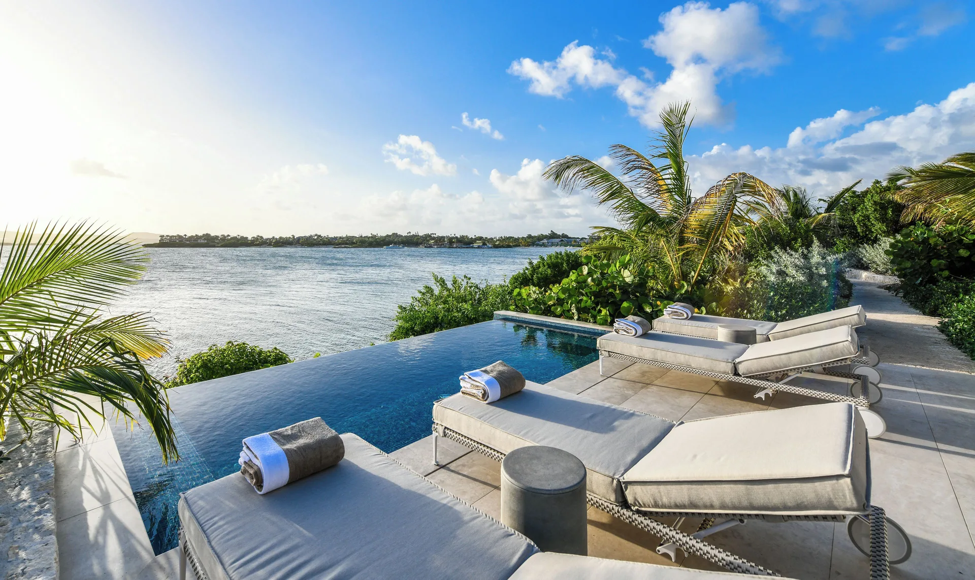 Delphis infinity pool deck with loungers overlooking the water at Jumby Bay Island.