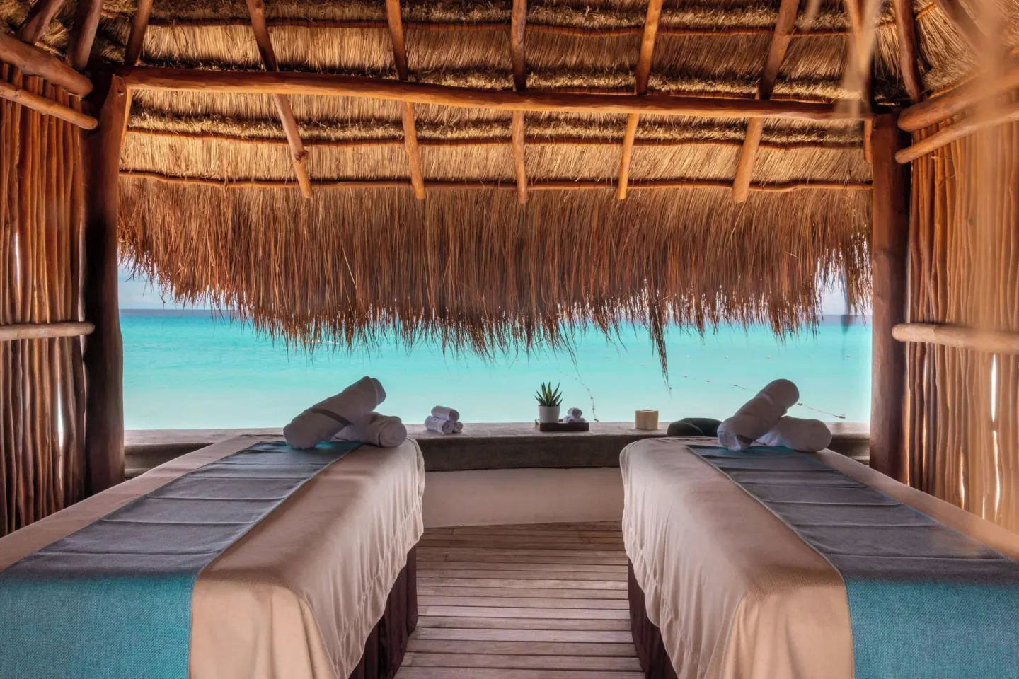 Two spa treatment beds in a thatched cabana at JW Marriott Cancun Resort & Spa.