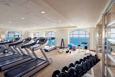 Fitness center with treadmills, weights, and arched ocean-view windows at JW Marriott Cancun Resort & Spa.