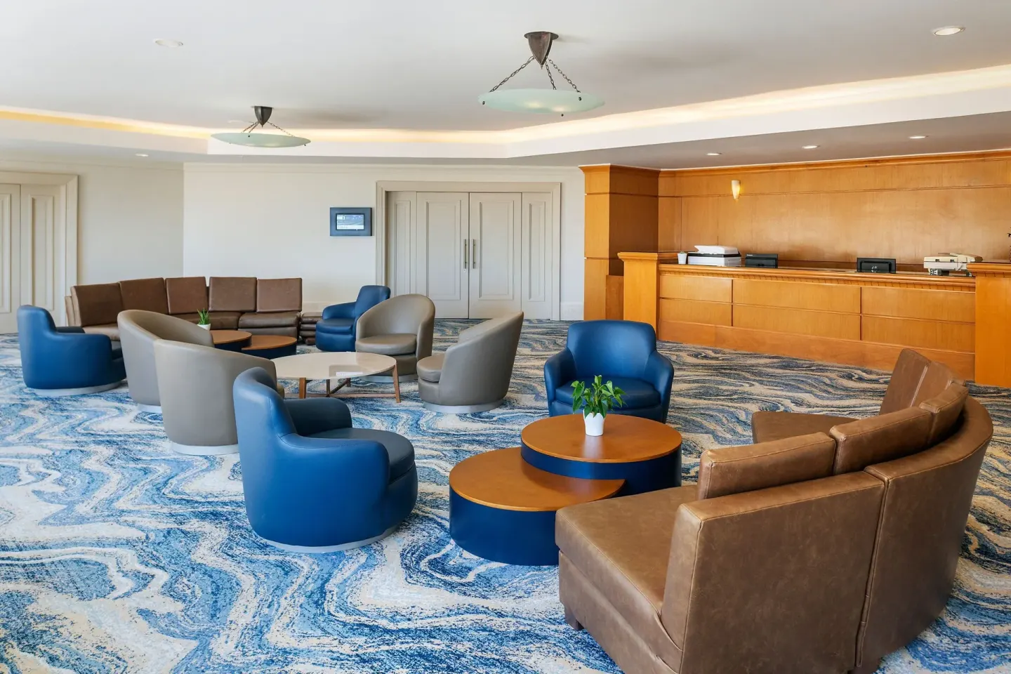 Lobby seating area with blue chairs and wood reception desk at JW Marriott Cancun Resort & Spa.