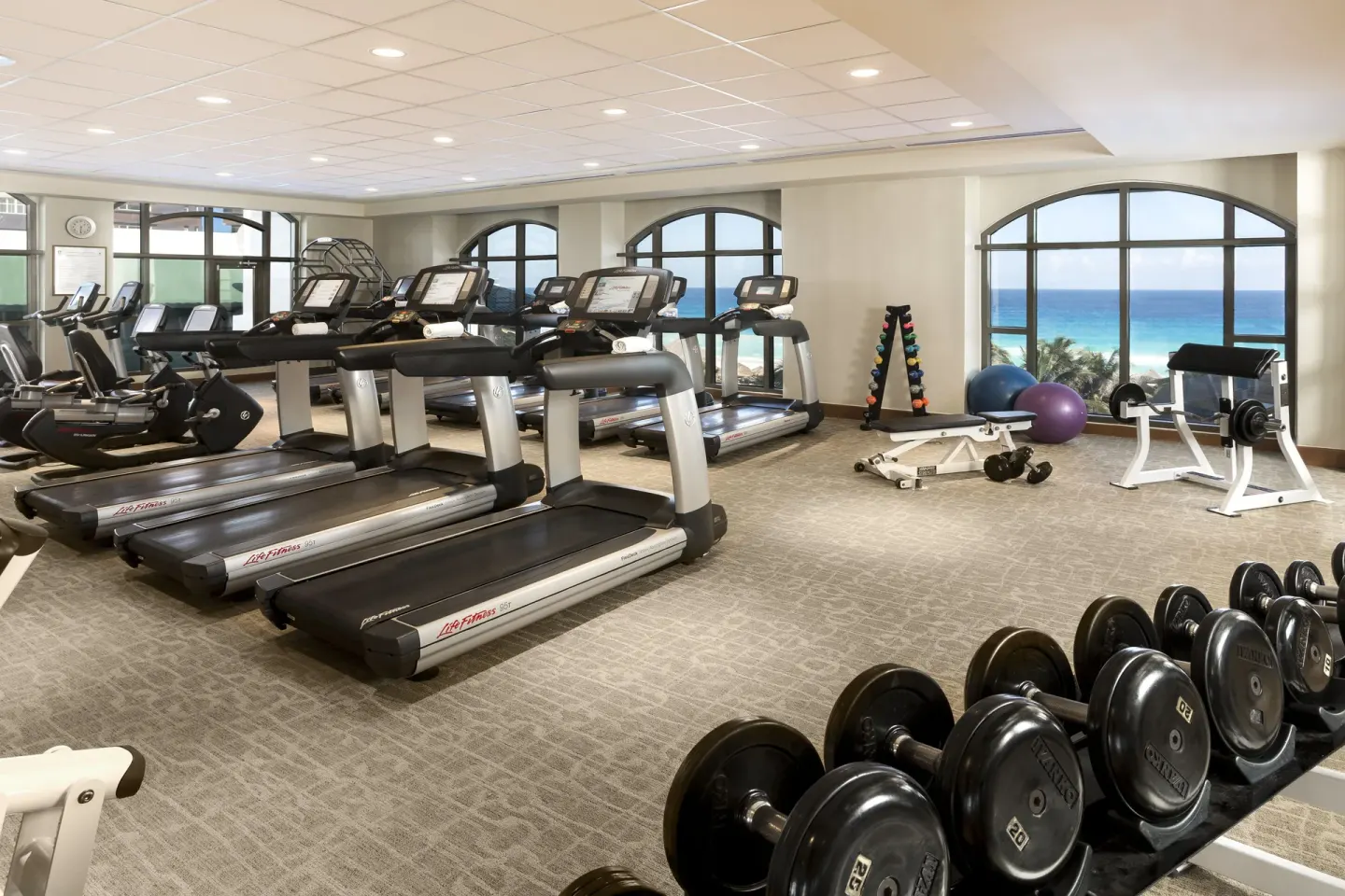 Fitness center with treadmills, weights and ocean-view windows at JW Marriott Cancun Resort & Spa.
