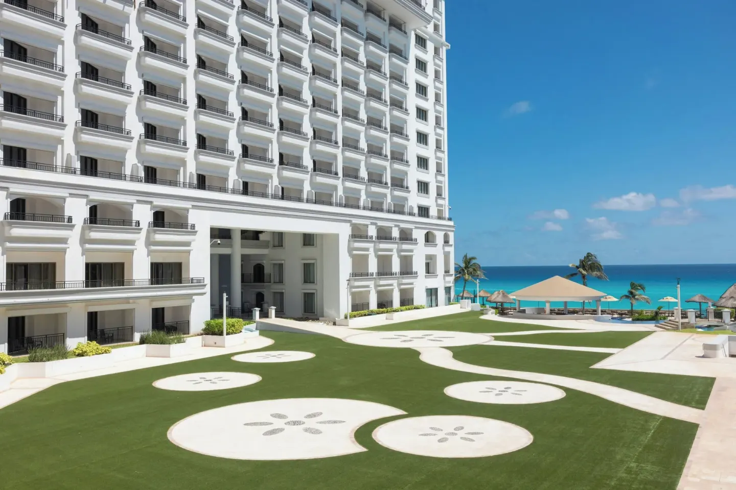 Oceanfront lawn and white hotel tower at JW Marriott Cancun Resort & Spa.