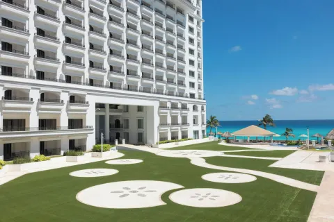 Oceanfront lawn and white hotel tower at JW Marriott Cancun Resort & Spa.