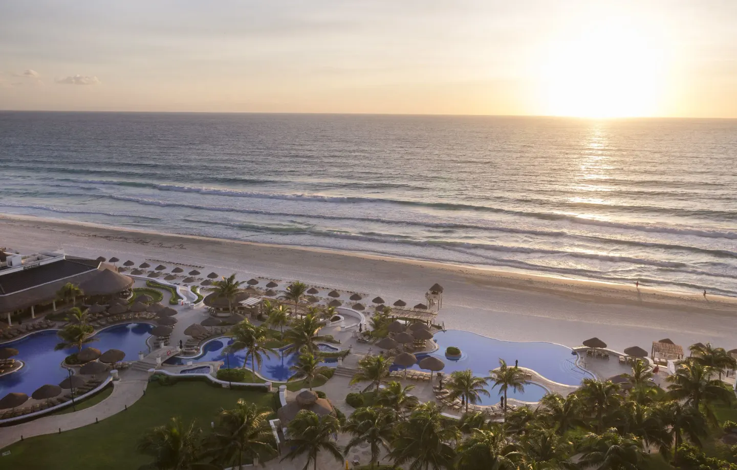 Oceanfront pools and beach at sunrise at JW Marriott Cancun Resort & Spa.