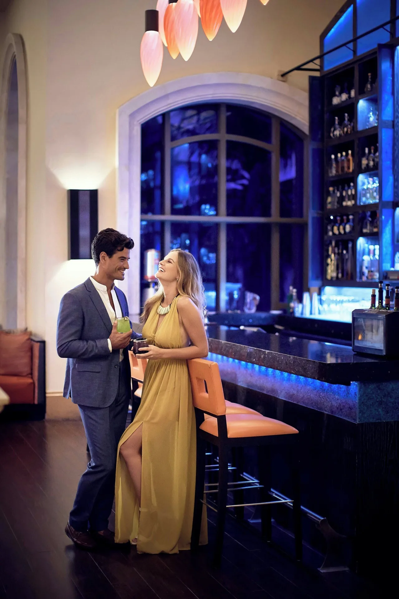 Couple with cocktails at a blue-lit bar inside JW Marriott Cancun Resort & Spa.
