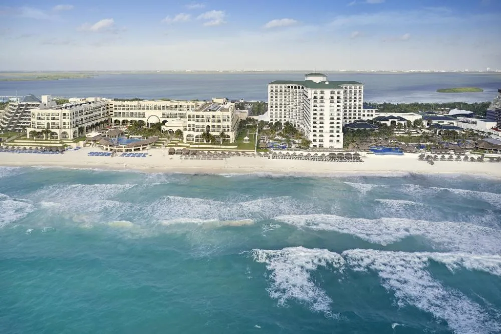 Aerial beachfront view of JW Marriott Cancun Resort & Spa beside turquoise surf and white sand.