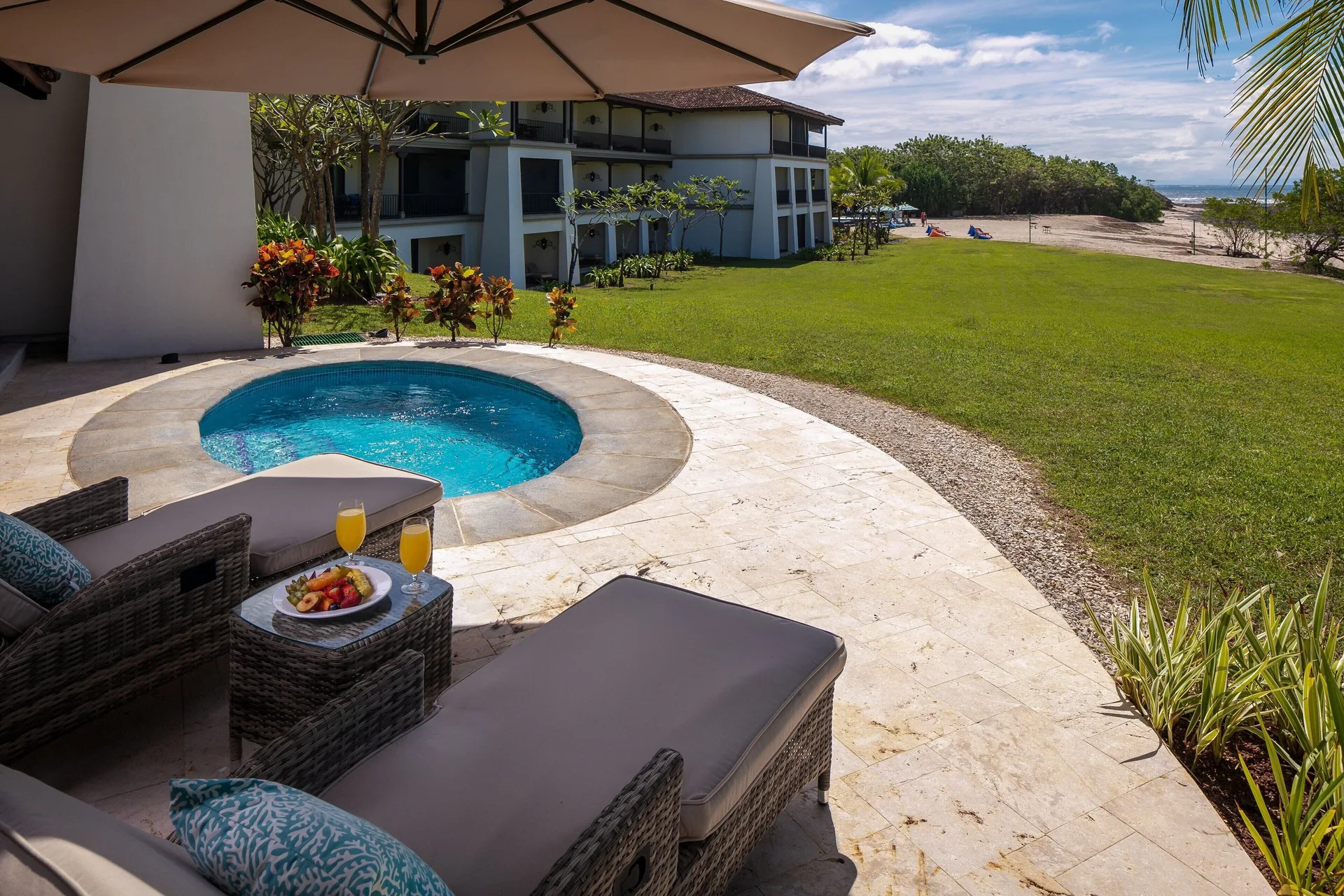 Beachfront plunge pool patio at JW Marriott Guanacaste Resort and Spa with loungers, lawn and ocean.