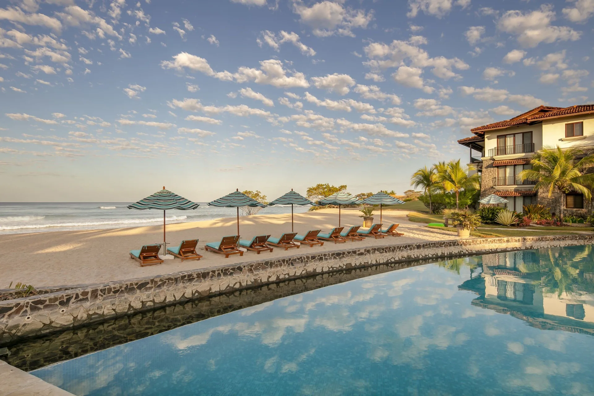 Beach loungers, umbrellas, pool, and ocean at JW Marriott Guanacaste Resort and Spa.