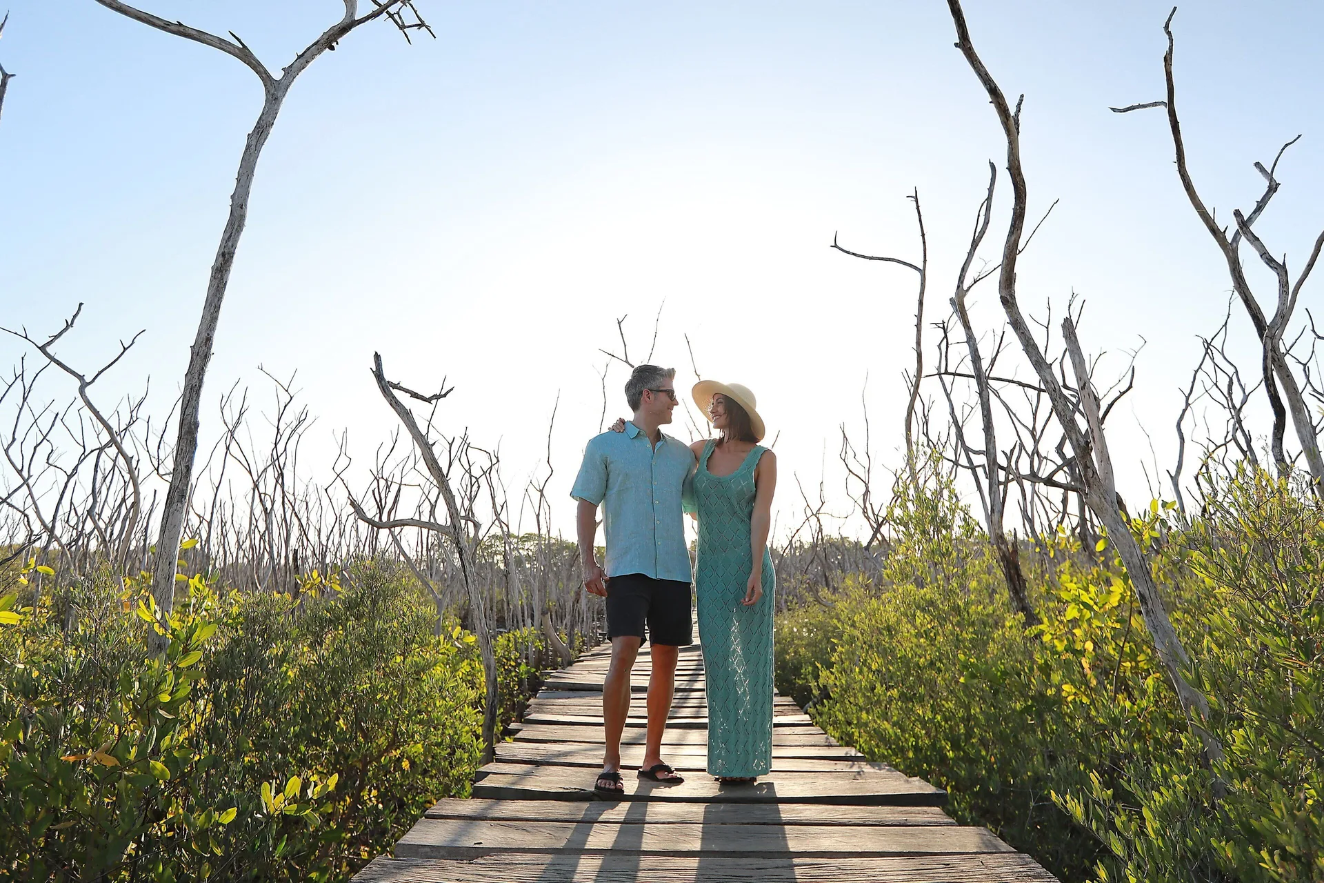 A couple walks along a wooden path through coastal trees at JW Marriott Guanacaste Resort and Spa.