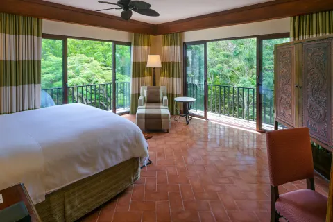 Corner king guest room at JW Marriott Guanacaste Resort and Spa with balconies overlooking dense greenery.