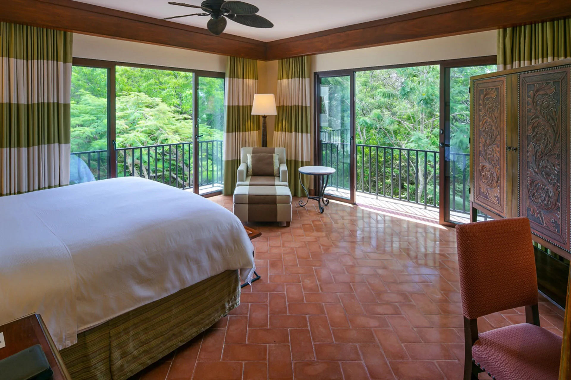 Corner king guest room at JW Marriott Guanacaste Resort and Spa with balconies overlooking dense greenery.