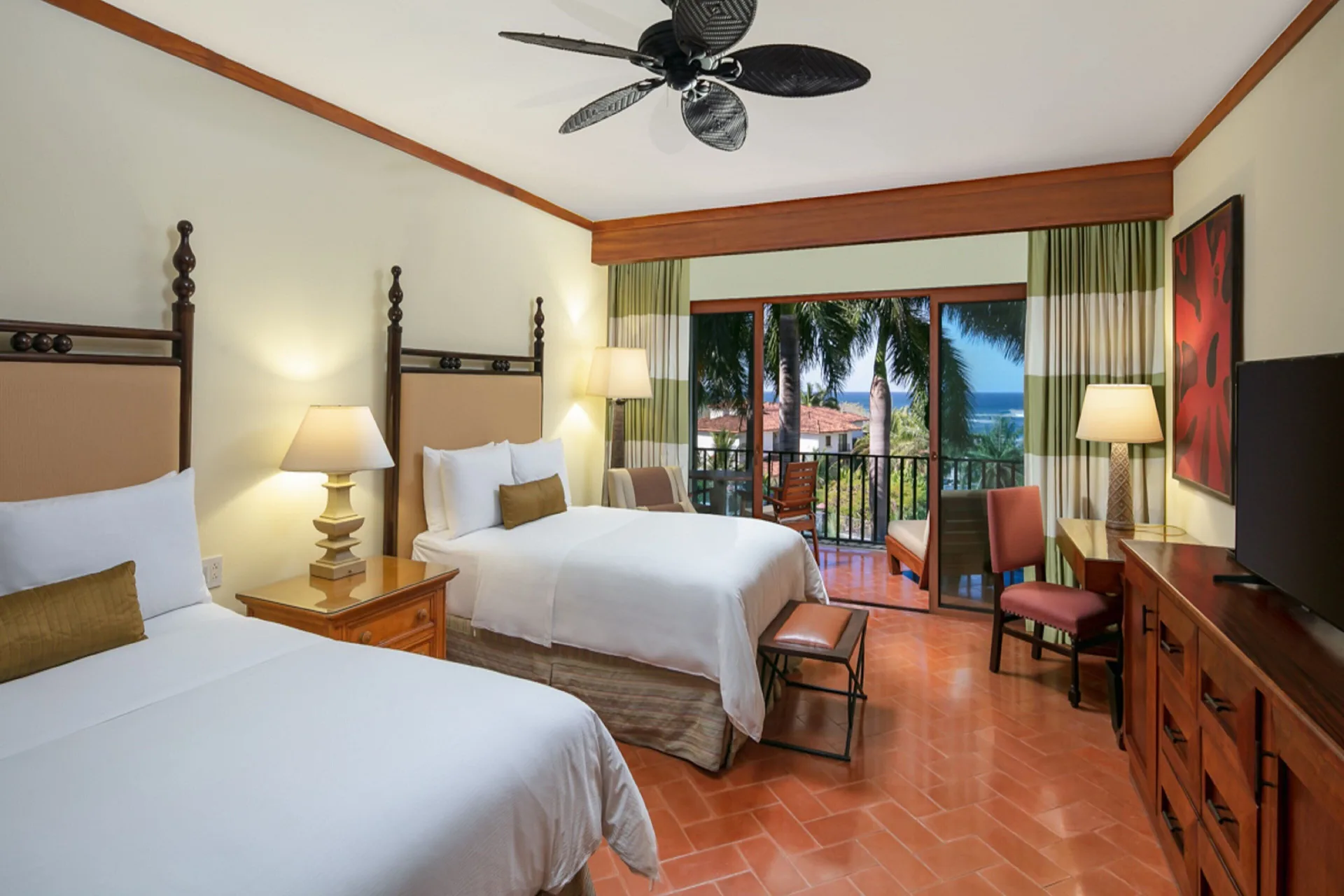 Two-bed guest room at JW Marriott Guanacaste Resort and Spa with balcony and ocean glimpses through palms.