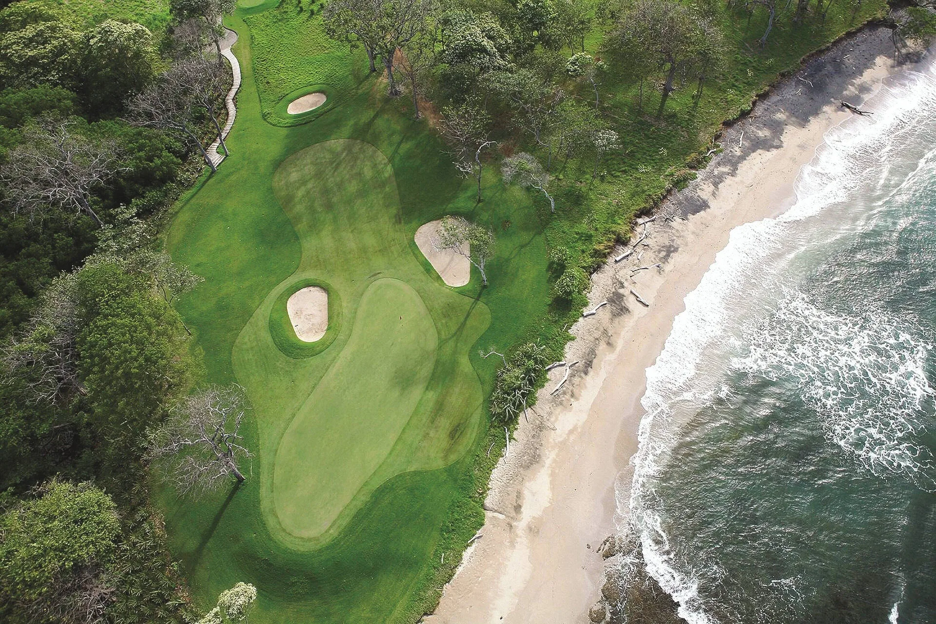 Aerial view of the oceanfront golf green and beach at JW Marriott Guanacaste Resort and Spa.