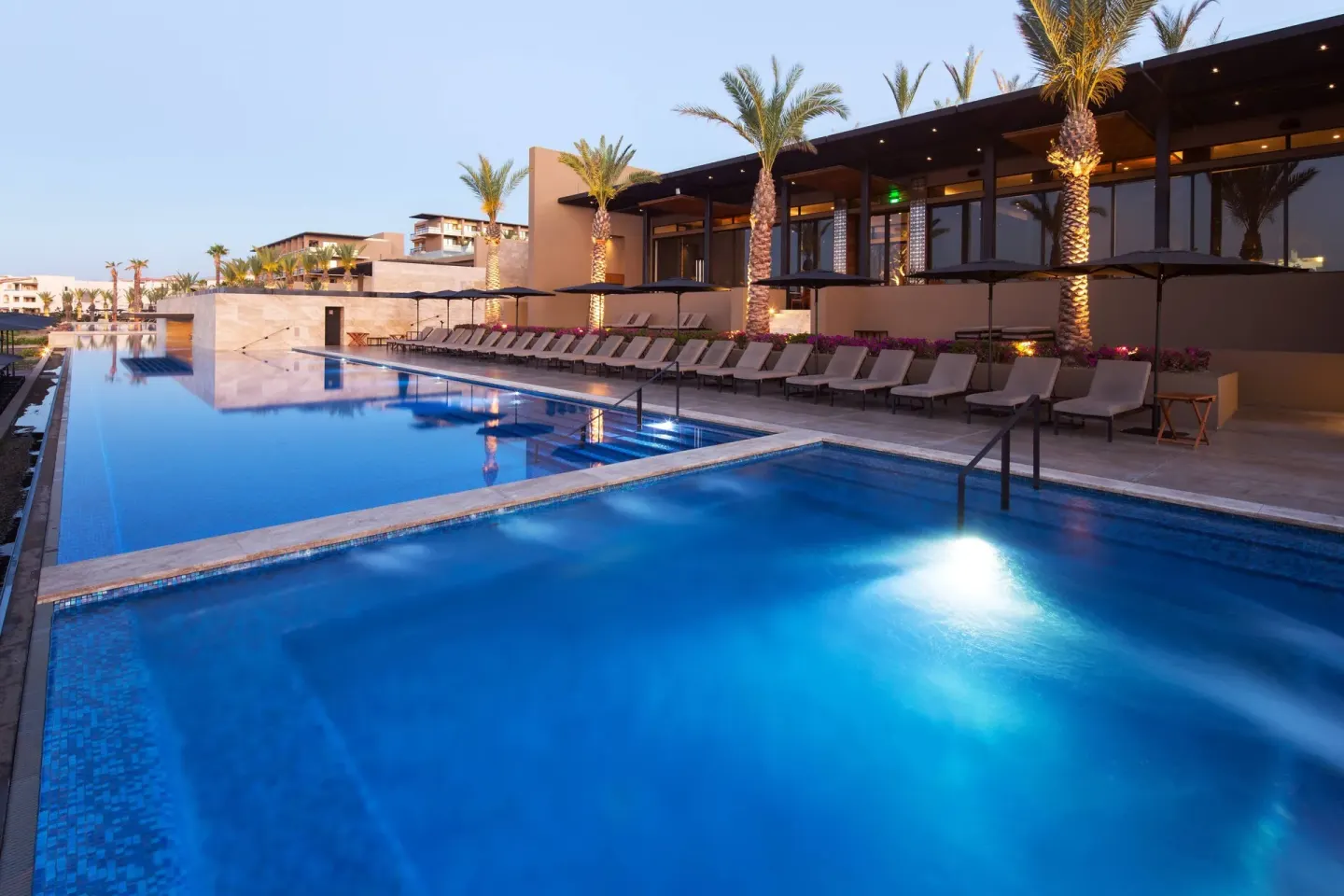 Evening pool deck with palms and lounge chairs at JW Marriott Los Cabos Beach Resort & Spa.