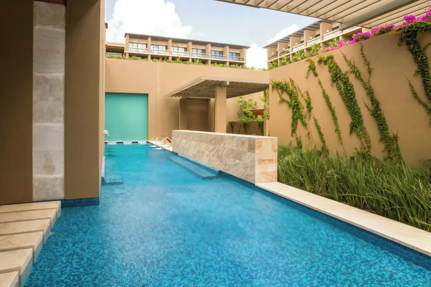 Narrow resort pool bordered by greenery at JW Marriott Los Cabos Beach Resort & Spa.