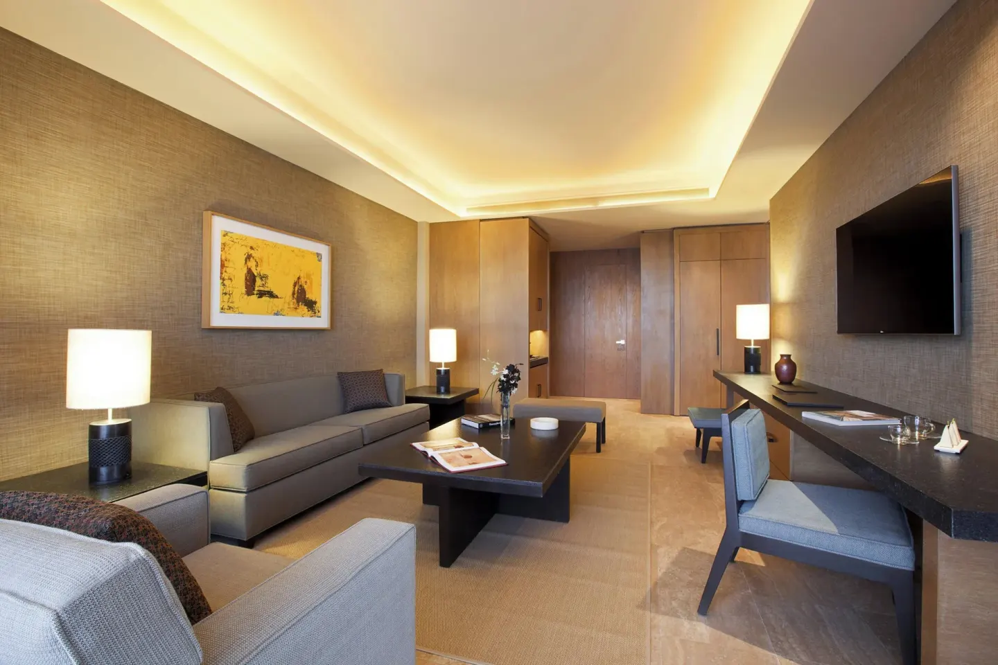 Guest room living area with sofa, desk and wall-mounted TV at JW Marriott Los Cabos Beach Resort & Spa.