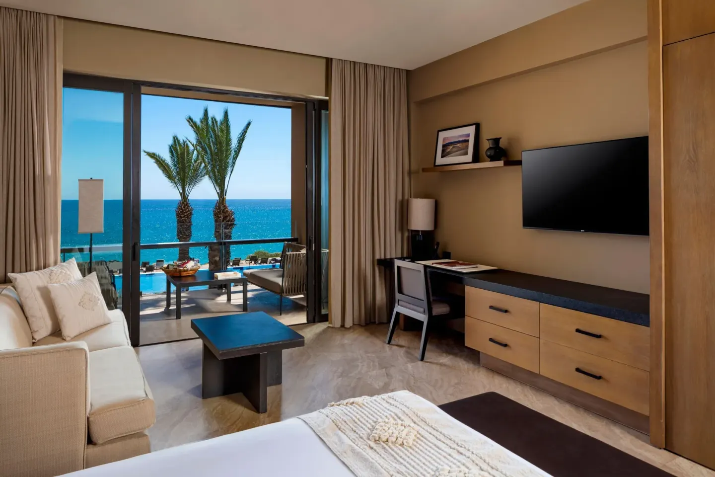 Guest room with bed, sofa, desk, and ocean balcony at JW Marriott Los Cabos Beach Resort & Spa.