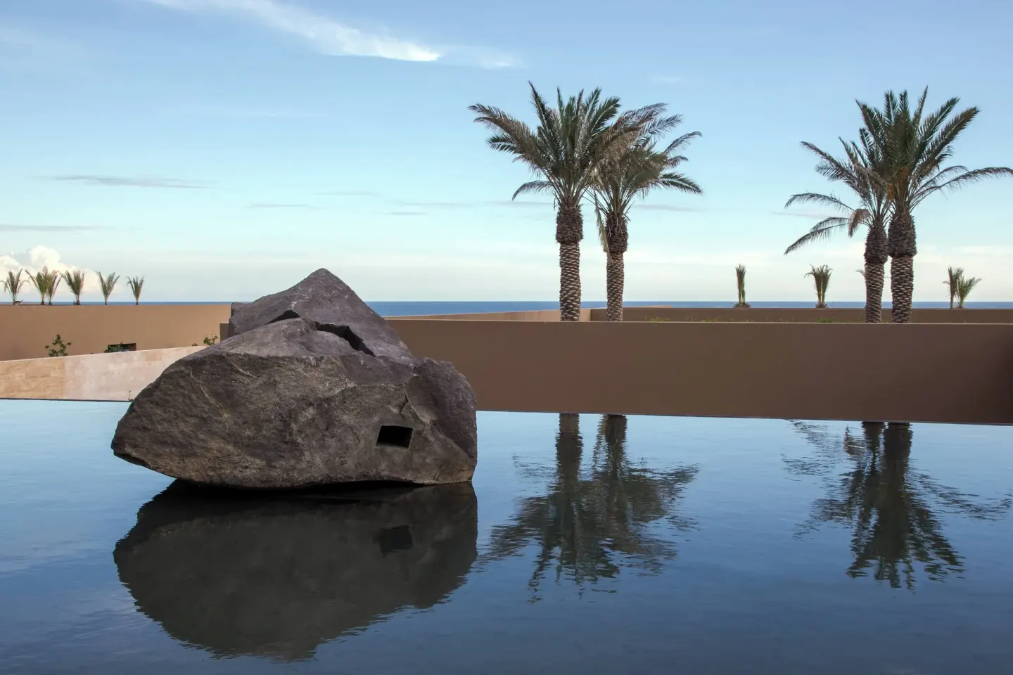 Reflecting pool with boulder sculpture and palms at JW Marriott Los Cabos Beach Resort & Spa.