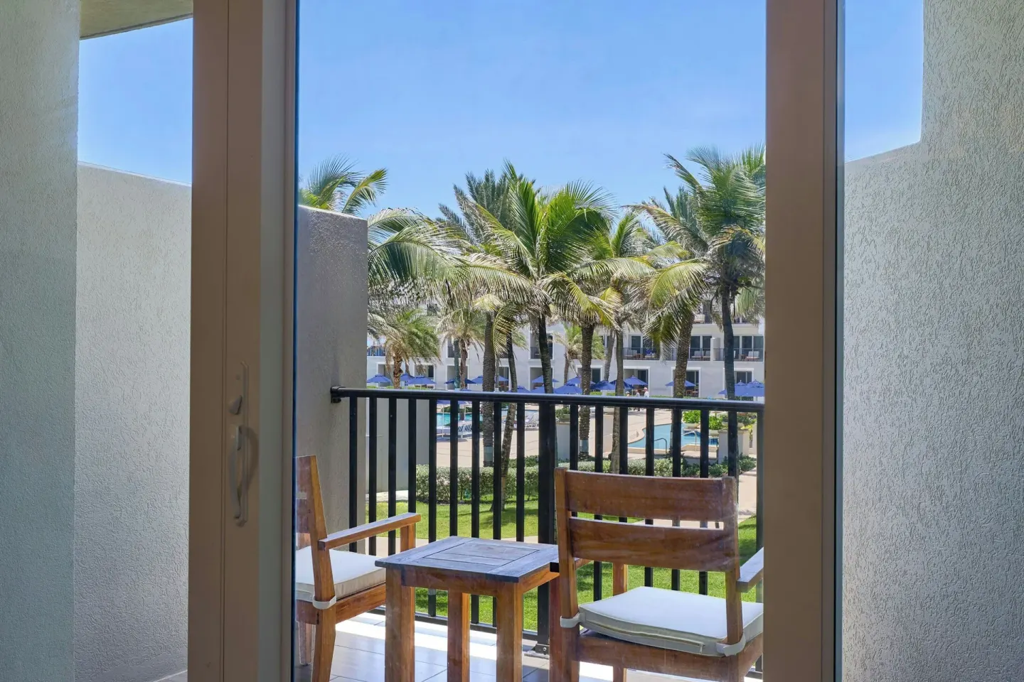 Balcony seating overlooking palms and pool at JW Marriott St. Maarten Beach Resort & Spa.