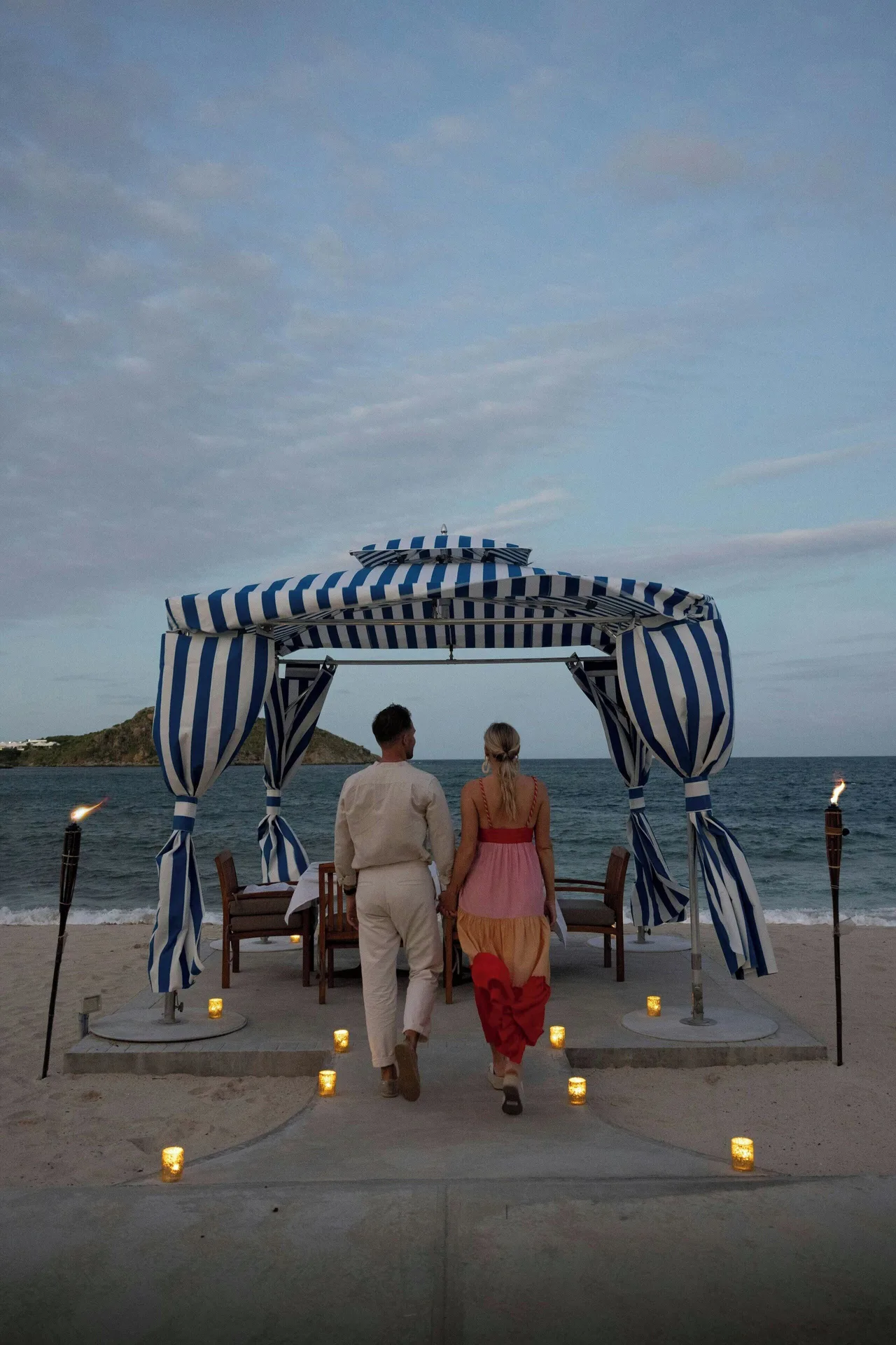 Couple walks to a striped beach cabana at JW Marriott St. Maarten Beach Resort & Spa.