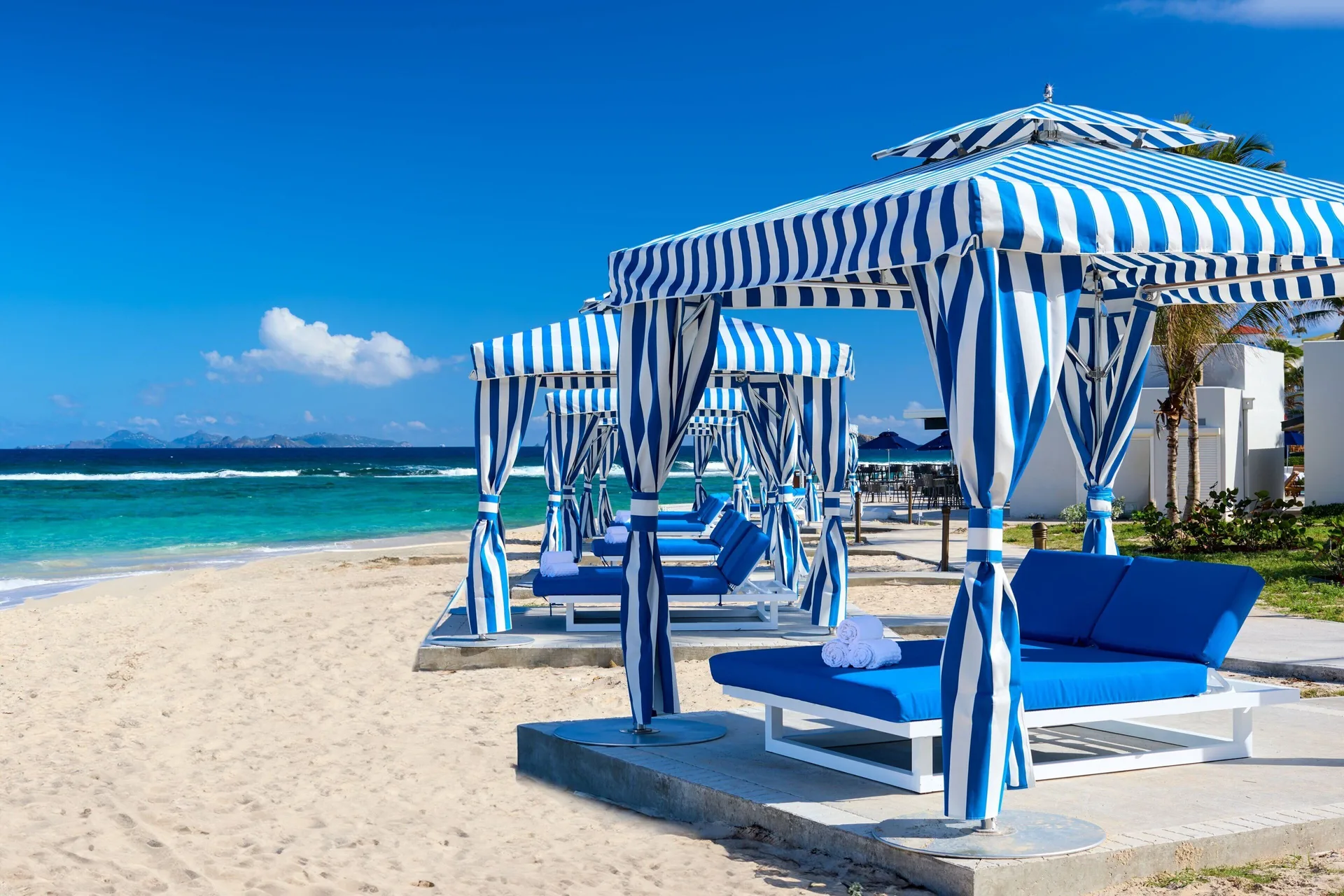 Striped cabanas and blue loungers on the beach at JW Marriott St. Maarten Beach Resort & Spa.