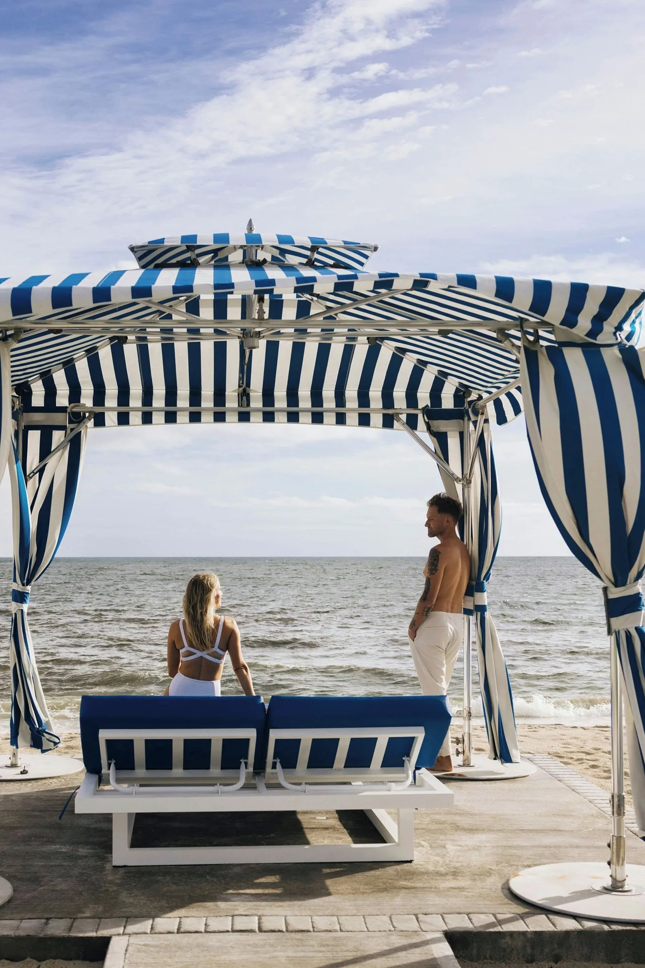 Guests relax under a striped beach cabana at JW Marriott St. Maarten Beach Resort & Spa.